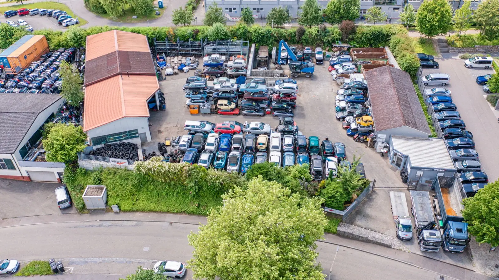 Luftaufnahme des Betriebsgeländes der Autoverwertung Weiser in Öhringen mit Hallen, Lagerflächen und abgestellten Fahrzeugen